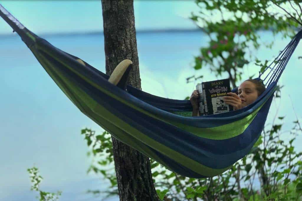 Daughter at inexpensive vacation home reading in hammock in backyard, on the coast; Acadia National Park adjacent